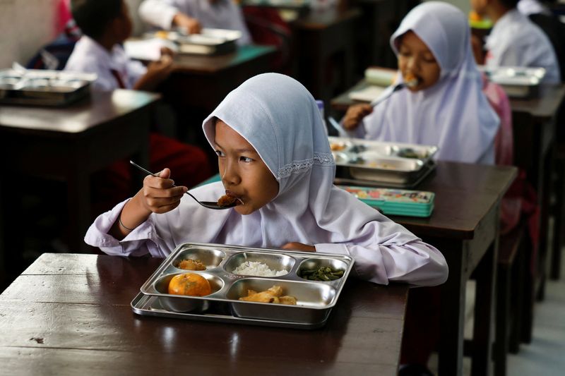 © Reuters. Học sinh ăn các bữa ăn từ chương trình bữa ăn dinh dưỡng miễn phí tại một trường học ở Jakarta, Indonesia, ngày 6 tháng 1 năm 2025. REUTERS/Willy Kurniawan